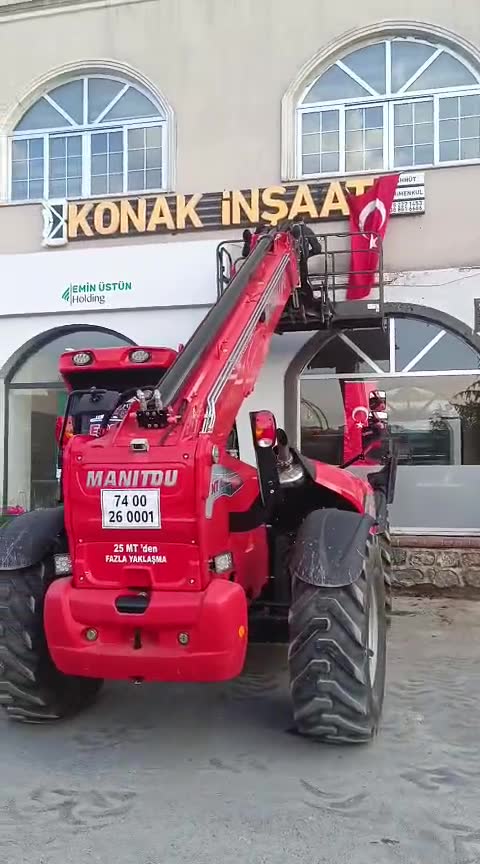 Manitou MT serisi teleskopik yükleyicinin arkadan görünümü, kol bina cephesine doğru uzanmış